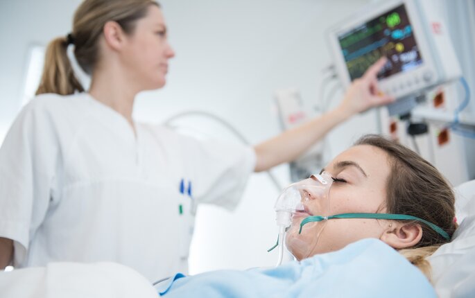 Bildet viser en sykepleier som pleier en pasient i sengen