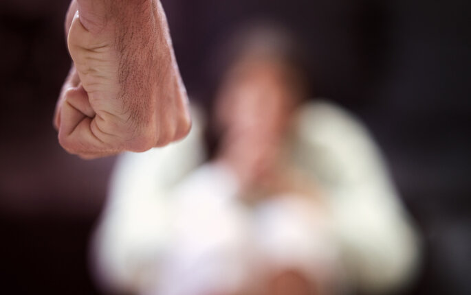 Bildet viser en knytteneve med en person i bakgrunnen som er redd Bildet viser en knytteneve med en person i bakgrunnen som er redd