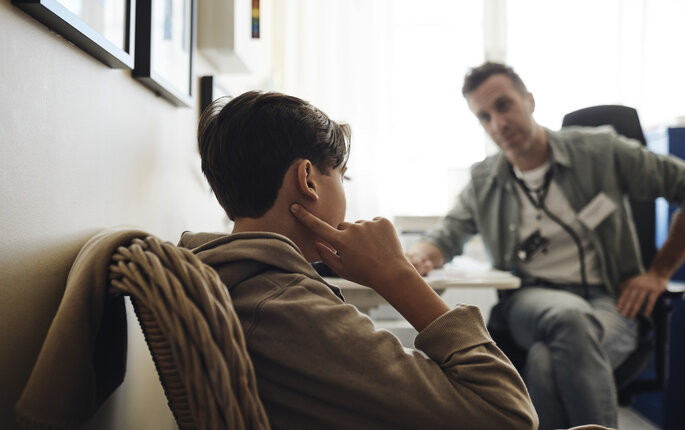 Bildet viser en ung gutt i samtale med en helsesykepleier.