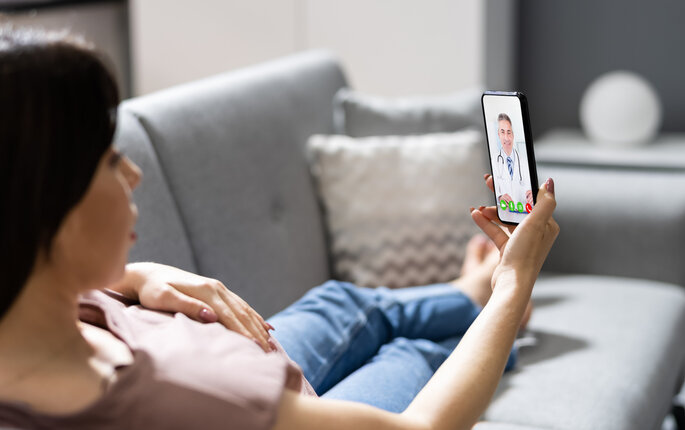 Bilde av person på sofa med mobiltelefon