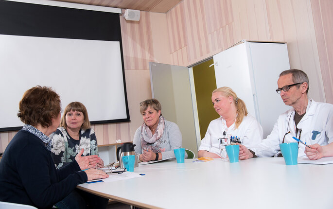 Bildet viser tverrfaglig helsepersonell som har møte rundt et bord.