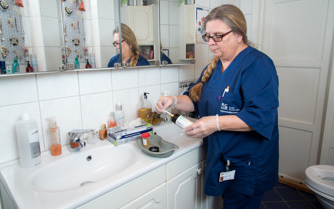 Sykepleier Gjertrud Langnes stikser en urinprøve i pasientens hjem, inne på badet.