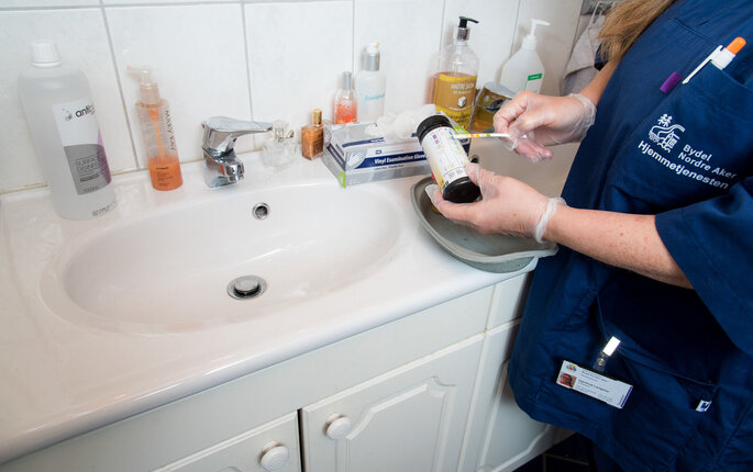 Bildet viser en hjemmesykepleier med en urinstrimmeltest på badet til brukeren