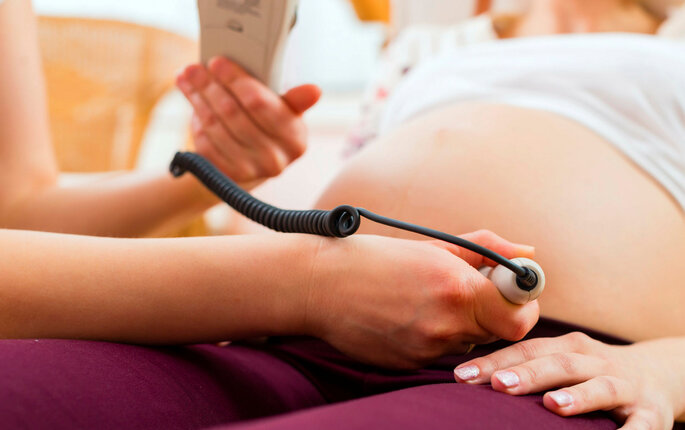 Bildet viser en jordmor som undersøker en gravid kvinne med CTG (kardiotokografi).