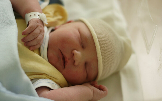 Bildet viser en nyfødt baby påkledd i sengen.
