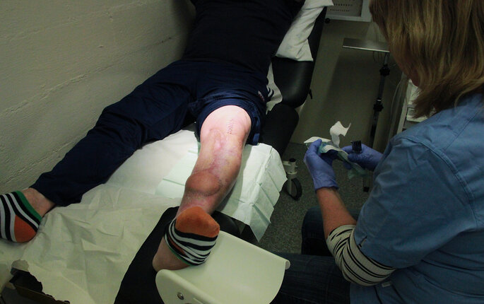 Sykepleier som utfører sårstell på en innsatt. Bildet viser en sykepleier som utfører sårstell på en innsatt.