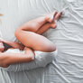 Bildet viser en kvinne som ligger i fosterstilling på en seng.