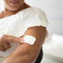 Bildet viser en kvinne som setter på et østrogen-plaster på overarmen.
