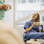 Bildet viser en sittende sykepleier som smiler og drikker kaffe