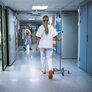 Bildet viser en sykepleier som går i en sykehuskorridor