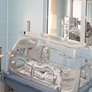 Bildet viser et nyfødt barn som ligger i en inkubator