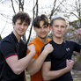 Bildet viser tre unge gutter i treningsklær som flekser muskler