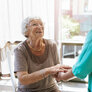 Bildet viser en hjemmeboende eldre kvinne som smiler til en sykepleier.