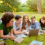 Bildet viser en gjeng studenter som jobber sammen på en laptop utendørs