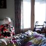 Bilde av eldre person på sengekanten på soverommet