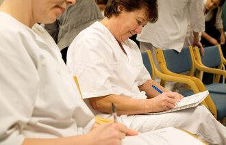 Bildet viser to sykepleiere som sitter og noterer