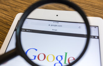  Bildet viser et forstørrelsesglass som holdes over Googles søkeside