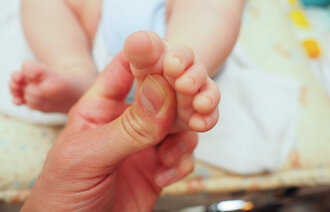 Bildet viser en baby som får massasje under den ene foten.
