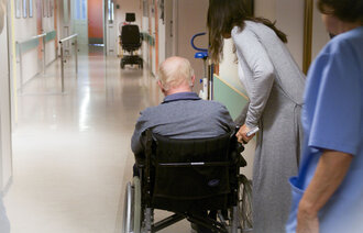 Bildet viser en eldre mann som får hjelp på et sykehjem.