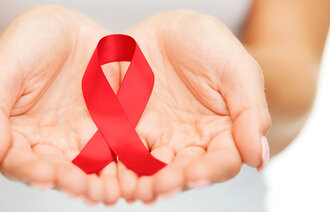 Bildet viser hender som holder en rød sløyfe som symboliserer hiv/aids