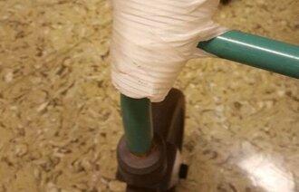 Bildet viser en plastkopp teipet fast foran nede på en rullator.