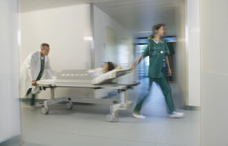 Bildet viser en lege og en sykepleier som triller en pasient