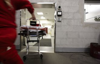 En mann i ambulanseuniform løper inn på sykehuset med en båre