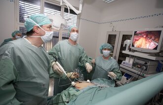 Kirurger utfører hysteroskopi, og følger med på en skjerm.