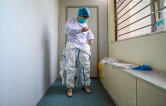 Bildet viser en lege som tar på seg smittevernutstyr.