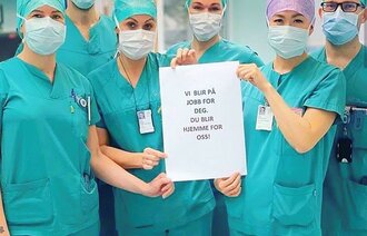 Bildet viser operasjonssykepleiere som holder opp et ark.