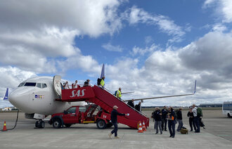 Bildet viser medisinsk innsatsteam på vei ut av et fly.