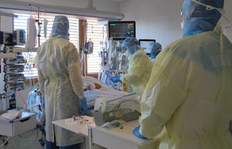 Bildet viser sykepleiere ved en pasient som er innlagt for covid-19, i en såkalt covid-kohort