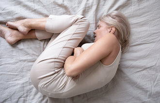 Bildet viser en kvinne som ligger i fosterstilling i en seng