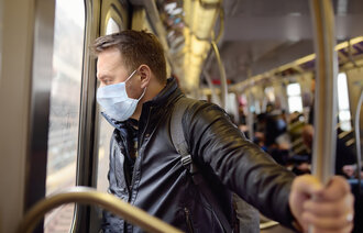 Bildet viser en ung mann som bruker munnbind under kollektivtransport