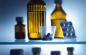 Bildet viser ulike flasker med legemidler, et brett med piller og et medisinbeger med piller.