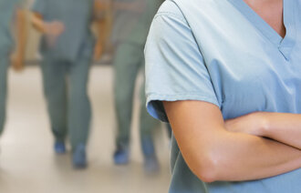 Bildet viser en sykepleier i forgrunnen med armene i kors