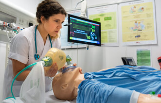 Bildet viser en sykepleierstudent som øver seg på en pasientdukke