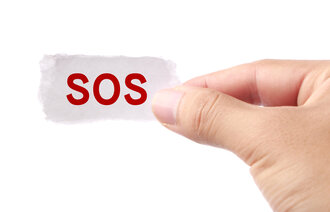 Bildet viser en hånd som holder en liten lapp påskrevet SOS