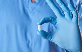 Bildet viser en sykepleier som holder rundt en pille. 