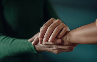 Bildet viser hendene til en kvinne som kjærlig holder rundt en annens hånd.