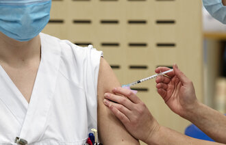 Bildet viser en helsearbeider som får koronavaksine.