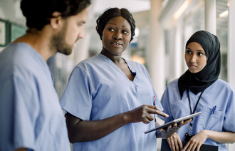 Bildet viser tre sykepleiere som står og prater sammen