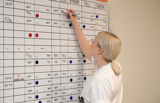 Bildet viser Annie Sjursen som skriver på pasienttavlen.
