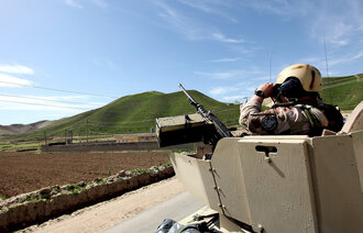 Bildet viser en tanks i Afghanistan. En norsk soldat står med kikkert opp av hullet i tanksen.
