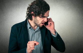 Bildet viser en sint mann som snakker i telefon
