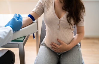 Bildet viser et helsepersonell som tar en blodprøve av en gravid kvinne