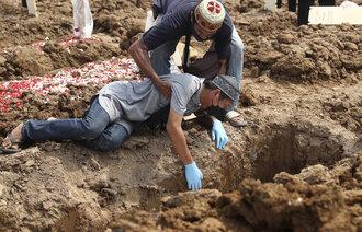 Bildet viser en mann som sørger ved siden av en grav over et familiemedlem som har dødd av covid-19