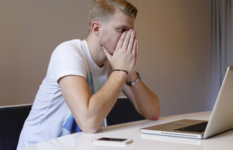 En sliten, ung mann ser på en dataskjerm