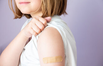 Bildet viser en jente som har plaster på overarmen etter å ha fått vaksine.