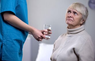 En sykepleier gir medisiner til en person med demens